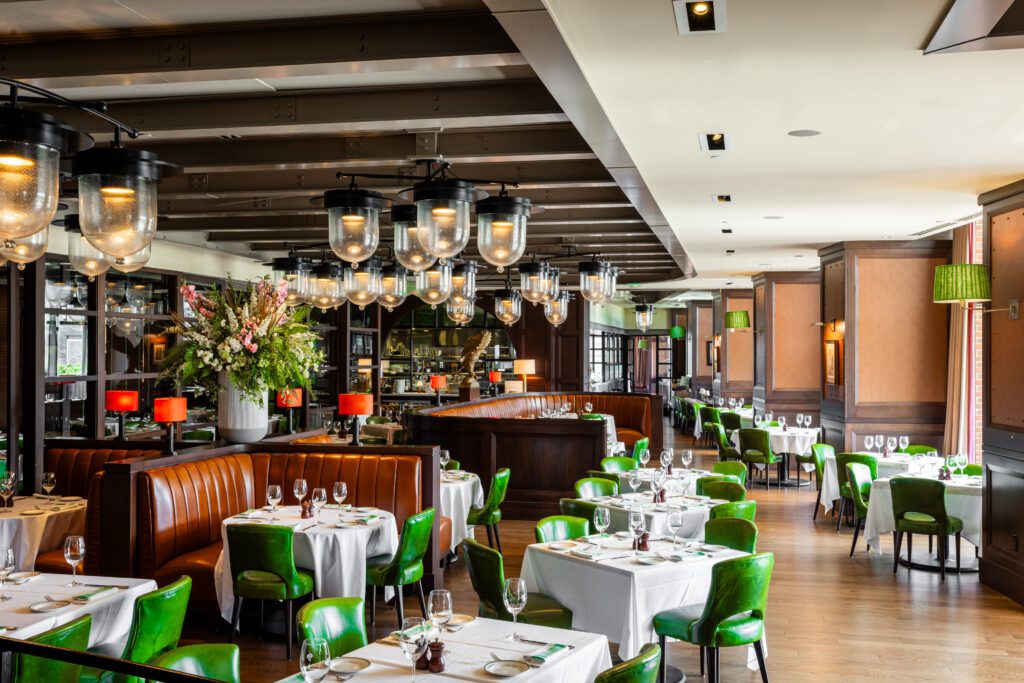 Dining room interior tables at Smith & Wollensky restaurant beside floor-to-ceiling windows overlooking the Fort Point Channel
