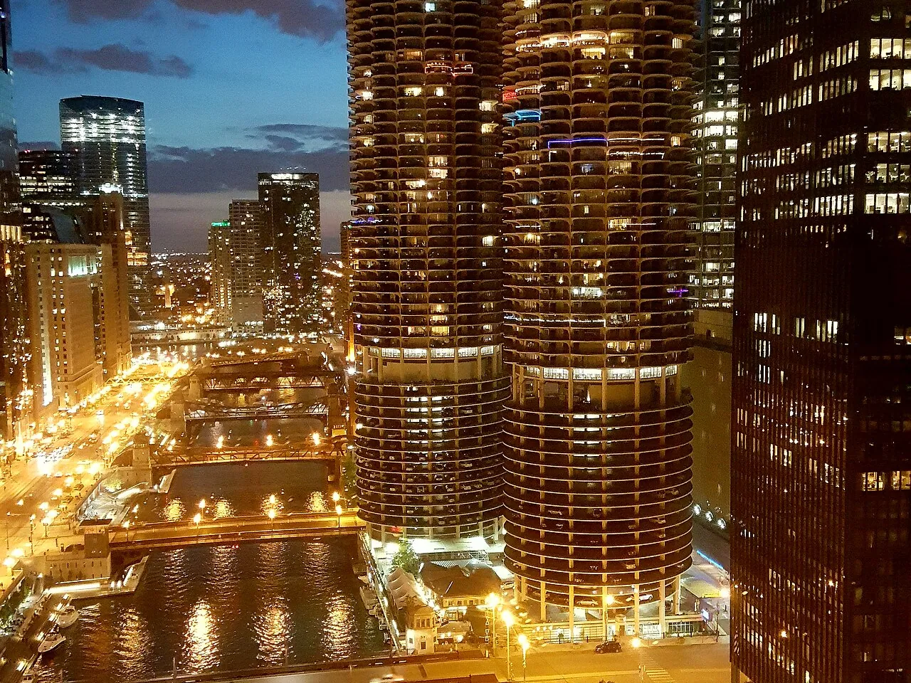The Chicago River at dusk, its bridges and Wacker Drive lit beside the Marina City towers