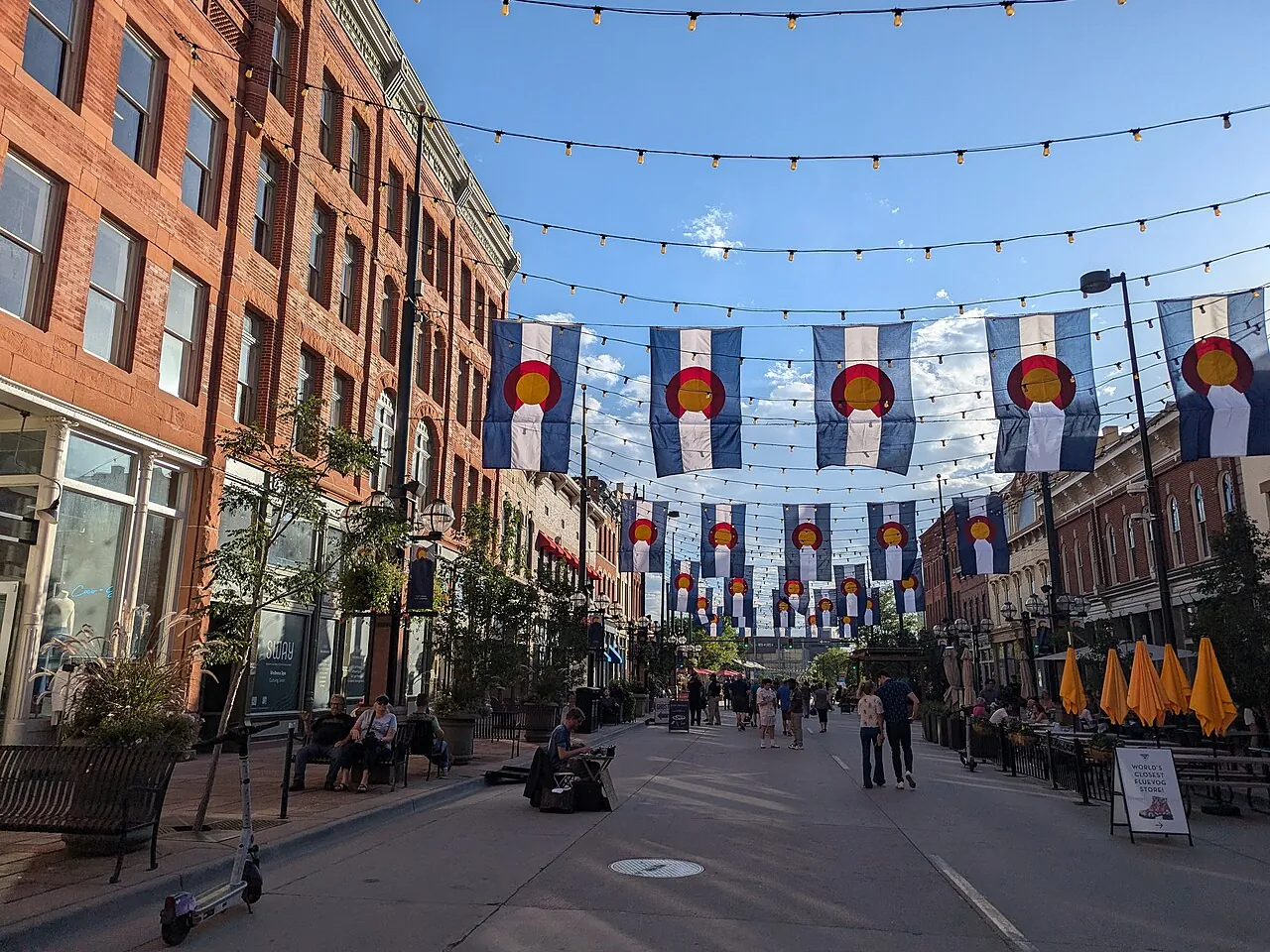Colorado flags and strings of lights over the brick storefronts of Larimer Square in Denver